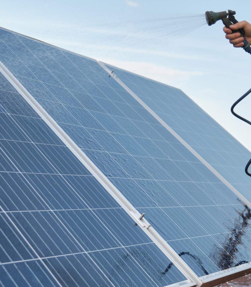 technician-cleaning-solar-panels-with-water